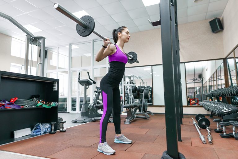 Young athletic woman exercising on the machines in modern sport gym. Fitness, sport, training, people, healthy lifestyle concept