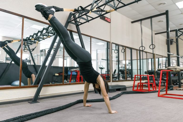 Young fitness woman doing exercises using the straps system in the gym. Sport, fitness, training, people concept